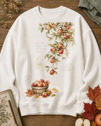 Women's white crewneck sweatshirt with apple branches and a harvest basket, front view.