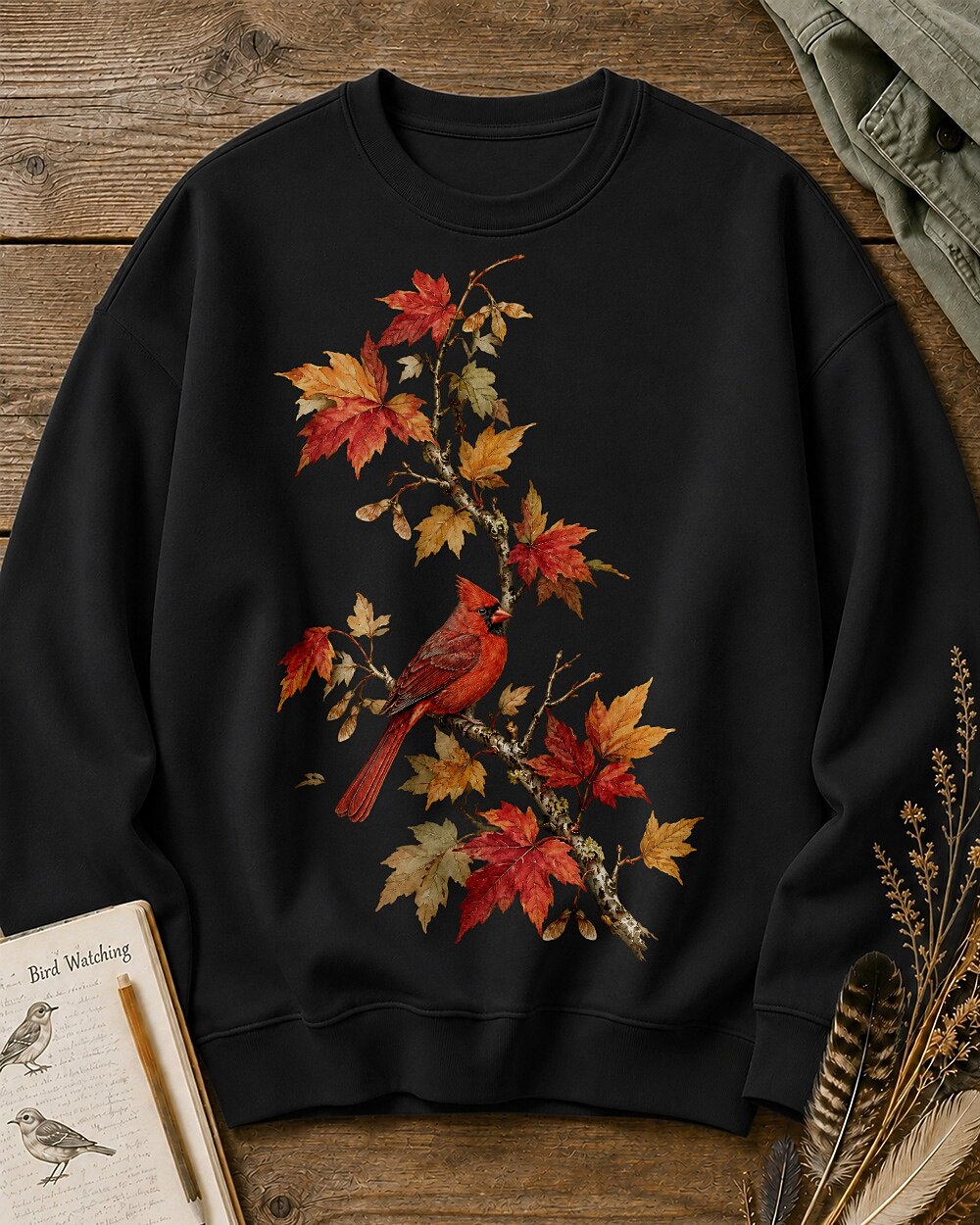 Women's black crewneck sweatshirt with a cardinal among orange autumn leaves, front view.