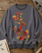 Women's gray crewneck sweatshirt with a cardinal among orange autumn leaves, front view.