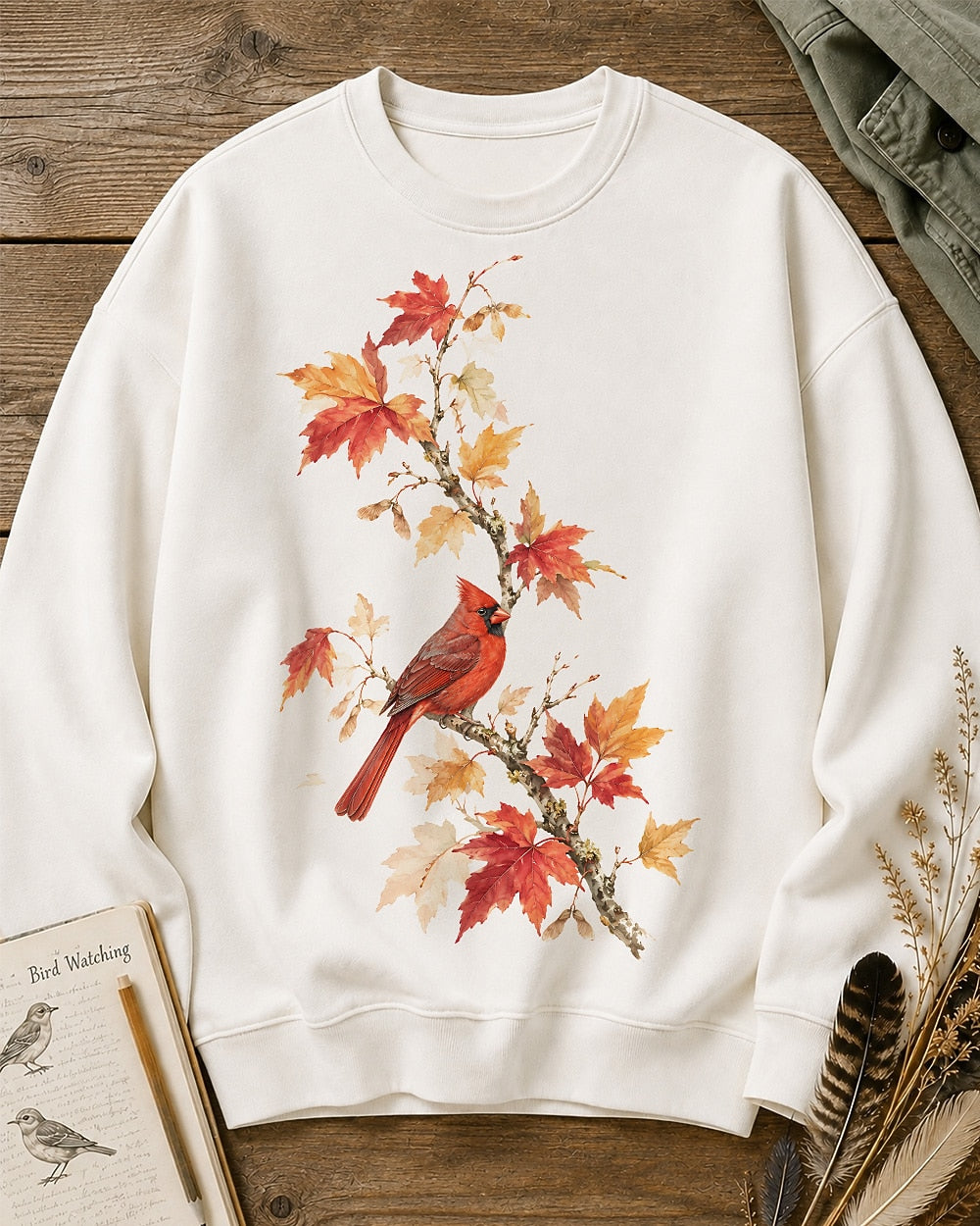Women's white crewneck sweatshirt with a cardinal among orange autumn leaves, front view.