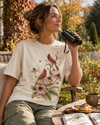 Woman wearing a off white cotton T-shirt with cardinals among pink coneflowers outdoors.