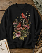 Women's black crewneck sweatshirt with cardinals among pink coneflowers, front view.