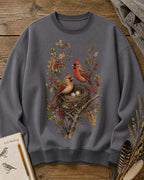 Women's gray crewneck sweatshirt with a cardinal pair beside a nest, front view.