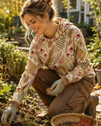 Woman wearing a yellow sun hoodie with an all-over coneflower and paisley pattern outdoors.