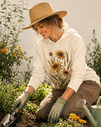 Woman wearing a light yellow sun hoodie with yellow coneflowers and wheat outdoors.