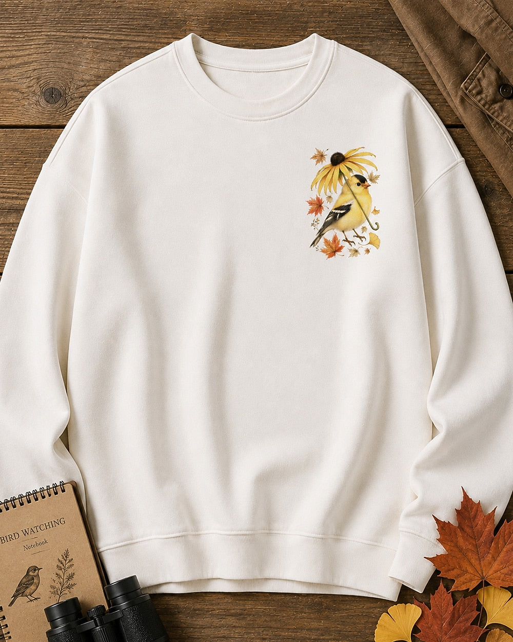 Women's white crewneck sweatshirt with a small goldfinch and flower chest print, front view.