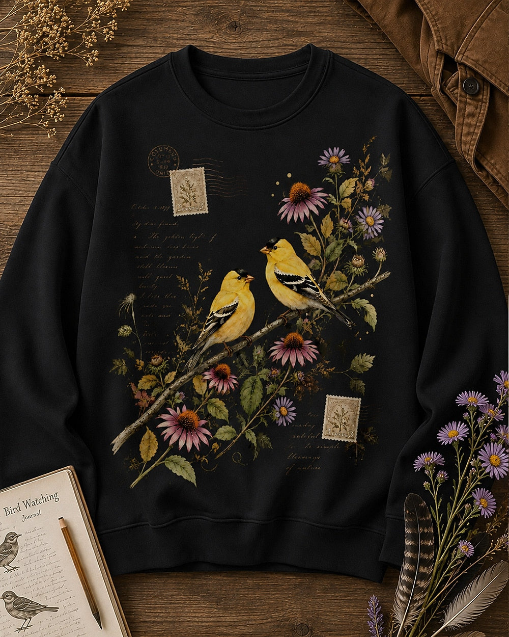 Women's black crewneck sweatshirt with two goldfinches among pink coneflowers, front view.
