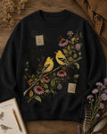 Women's black crewneck sweatshirt with two goldfinches among pink coneflowers, front view.