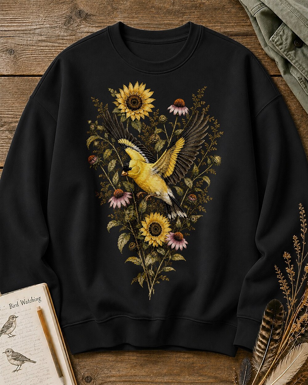 Women's black crewneck sweatshirt with goldfinches in flight among sunflowers, front view.