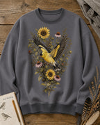 Women's gray crewneck sweatshirt with goldfinches in flight among sunflowers, front view.