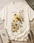 Women's off white cotton T-shirt with a goldfinch among yellow flowers, front view.