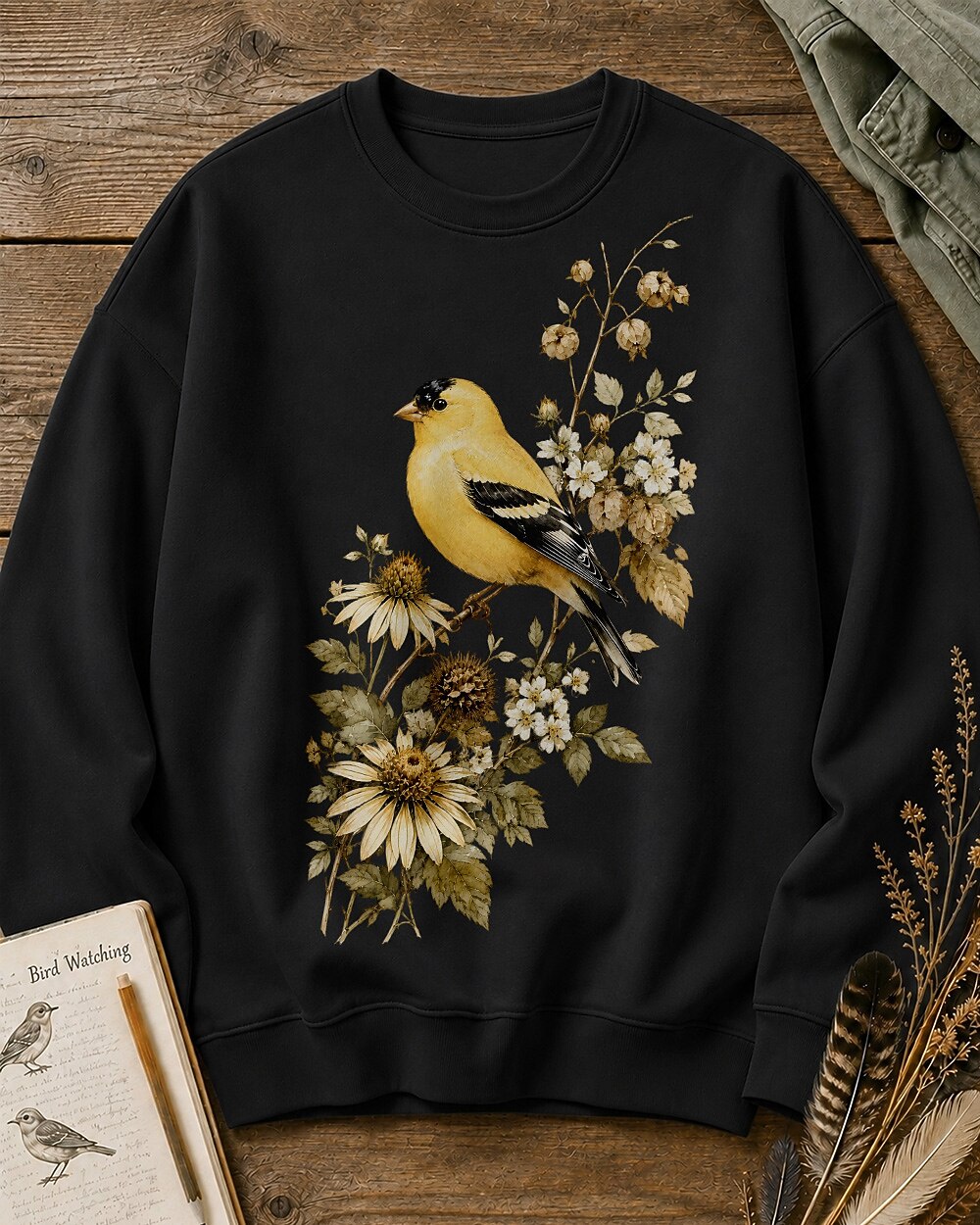 Women's black crewneck sweatshirt with a goldfinch among yellow flowers, front view.