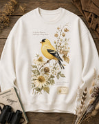 Women's white crewneck sweatshirt with a goldfinch among yellow flowers, front view.
