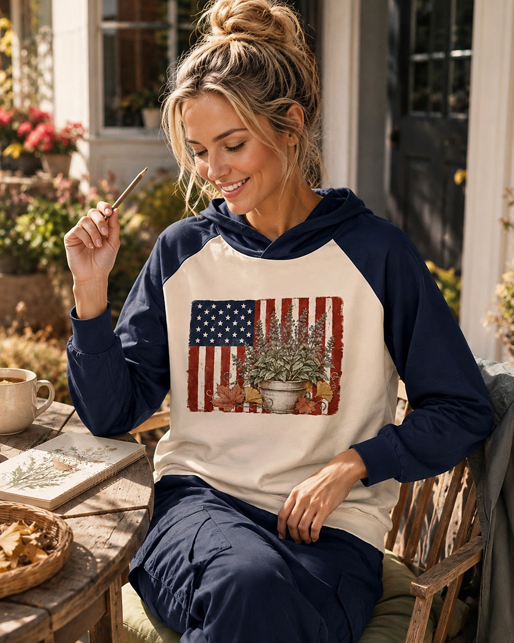 Woman wearing a navy cream sun hoodie with potted herbs and an American flag outdoors.