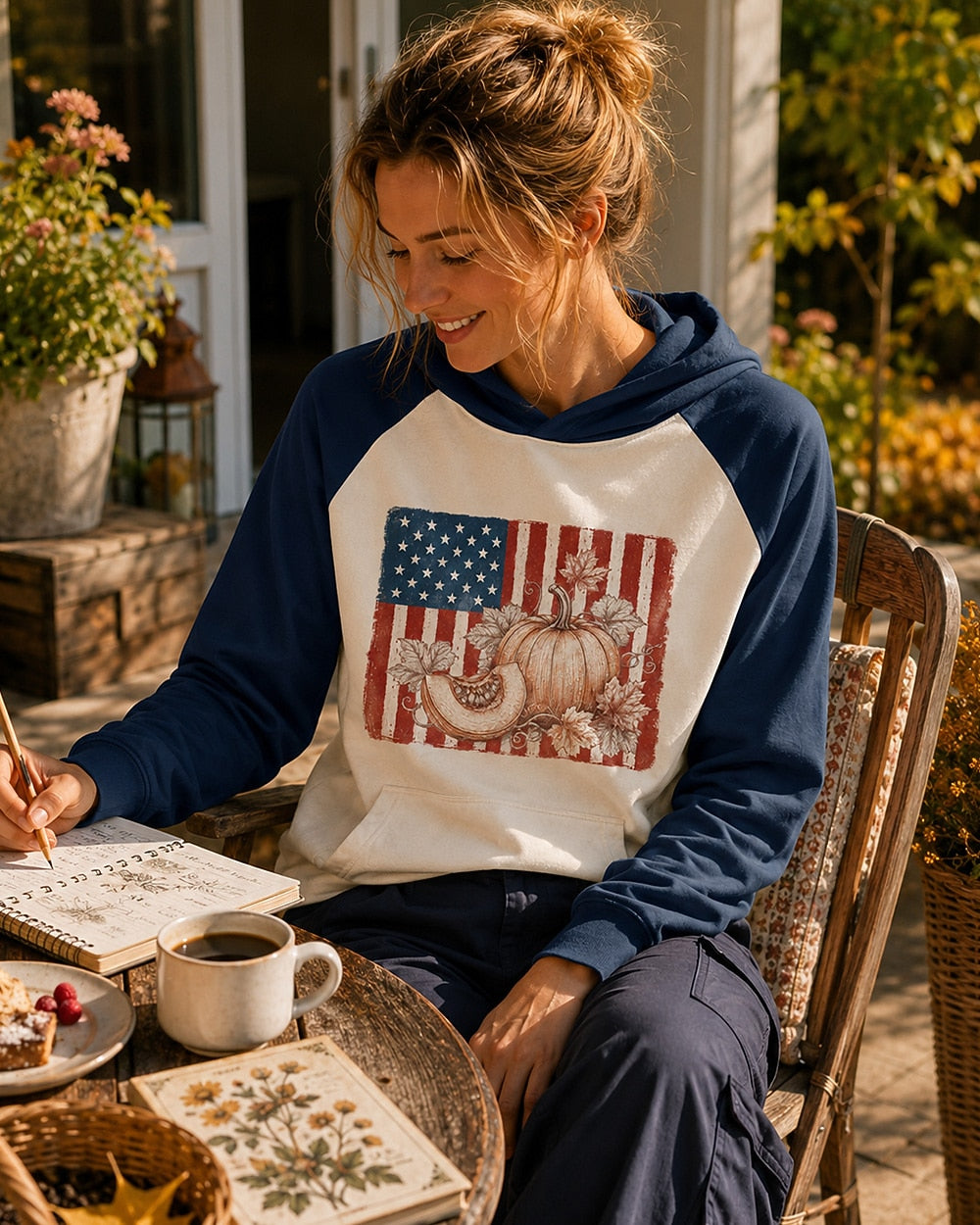 Woman wearing a navy cream sun hoodie with pumpkins and an American flag outdoors.