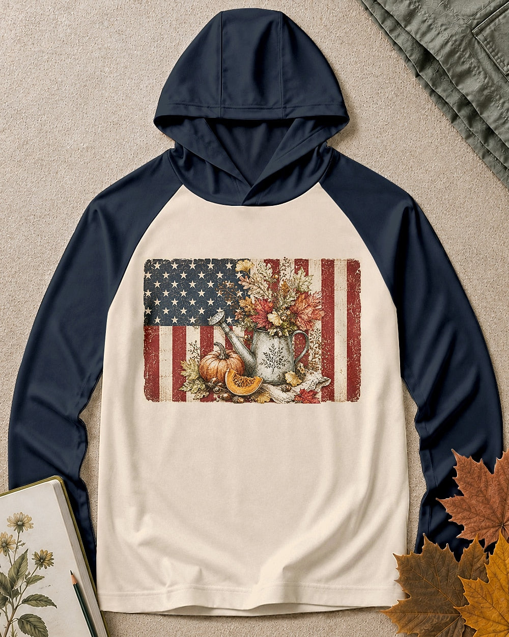 Women's cream sun hoodie with navy sleeves and an American flag, pumpkin and watering can graphic, front view.