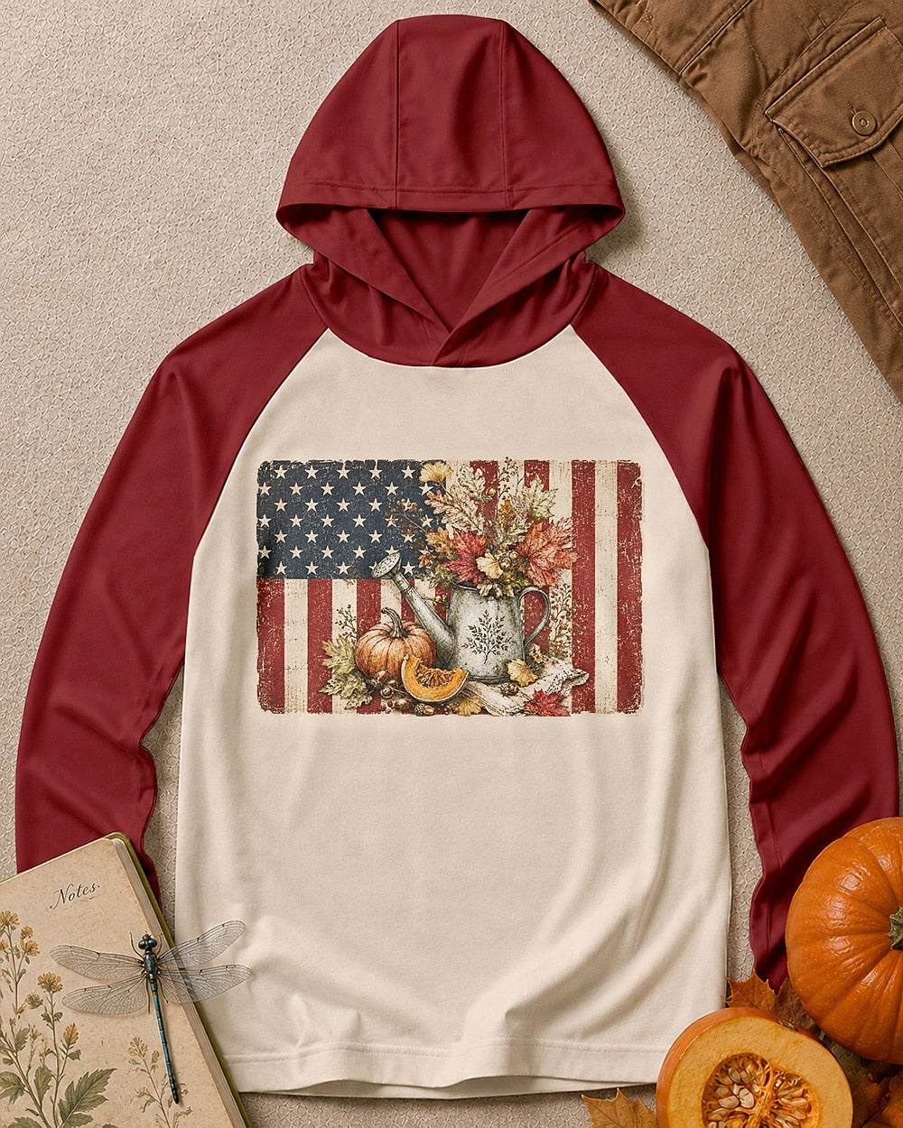 Women's cream sun hoodie with red sleeves and an American flag, pumpkin and watering can graphic, front view.