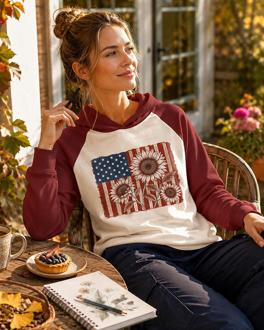Woman wearing a red cream sun hoodie with red sunflowers and an American flag outdoors.