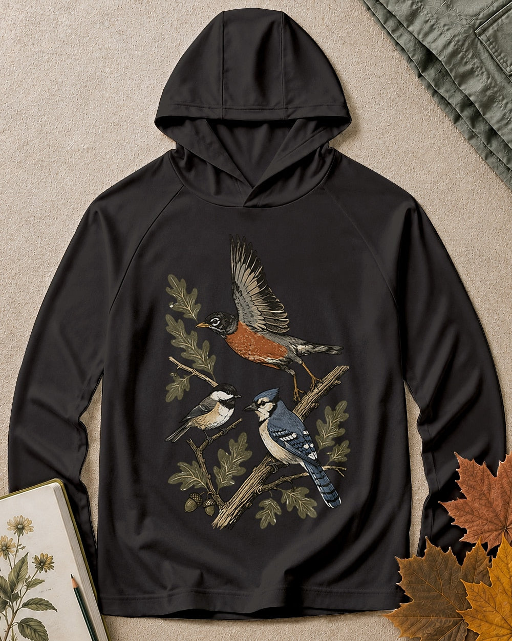 Women's black sun hoodie with a flying robin and blue jay among branches, front view.
