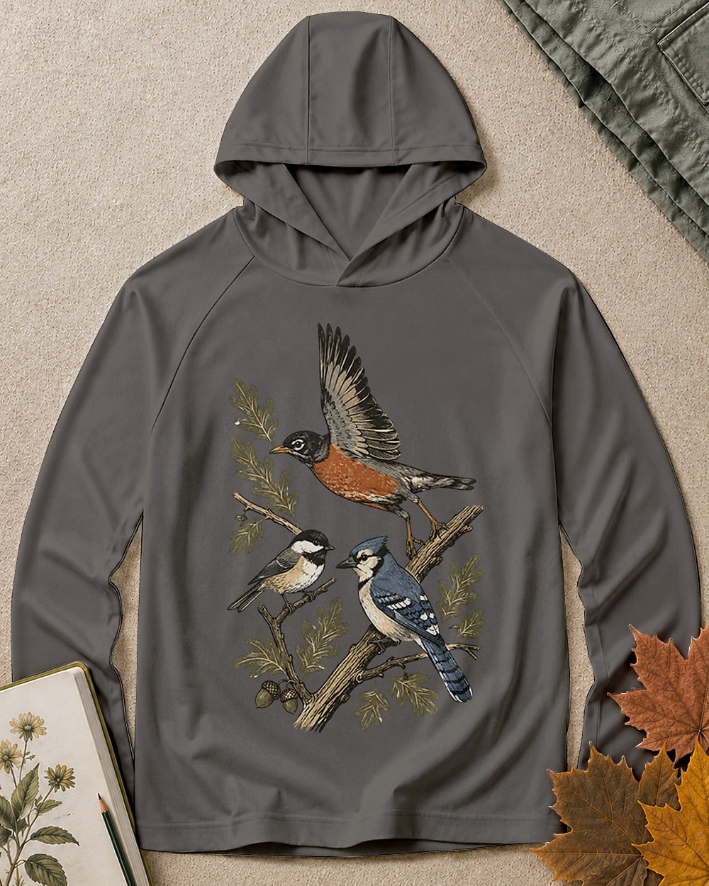 Women's dark grey sun hoodie with a flying robin and blue jay among branches, front view.