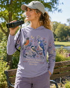 Woman wearing a violet sun hoodie with robins, chickadees, blue jays and wildflowers outdoors.