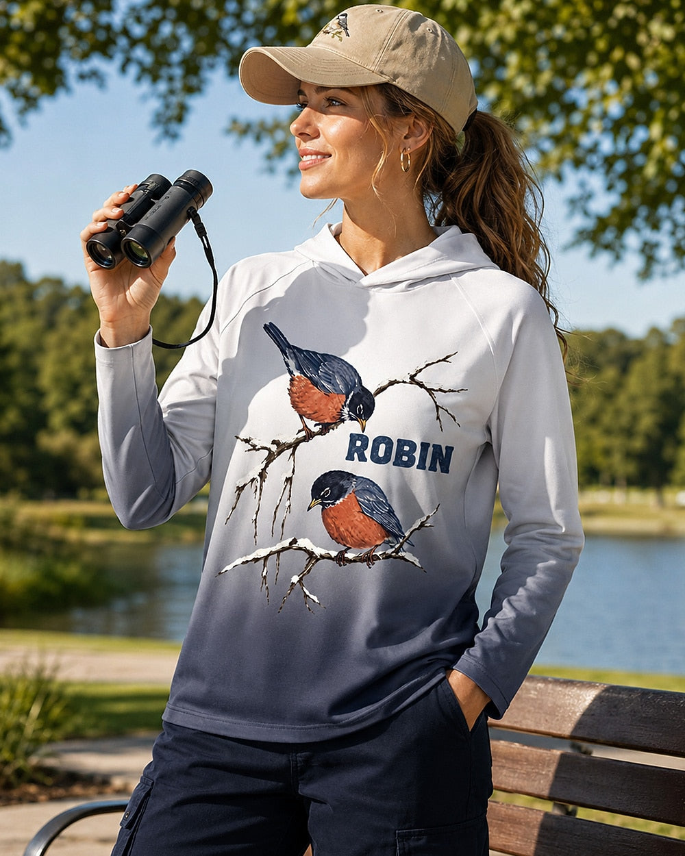 Woman wearing a white navy ombre sun hoodie with two robins on bare branches outdoors.