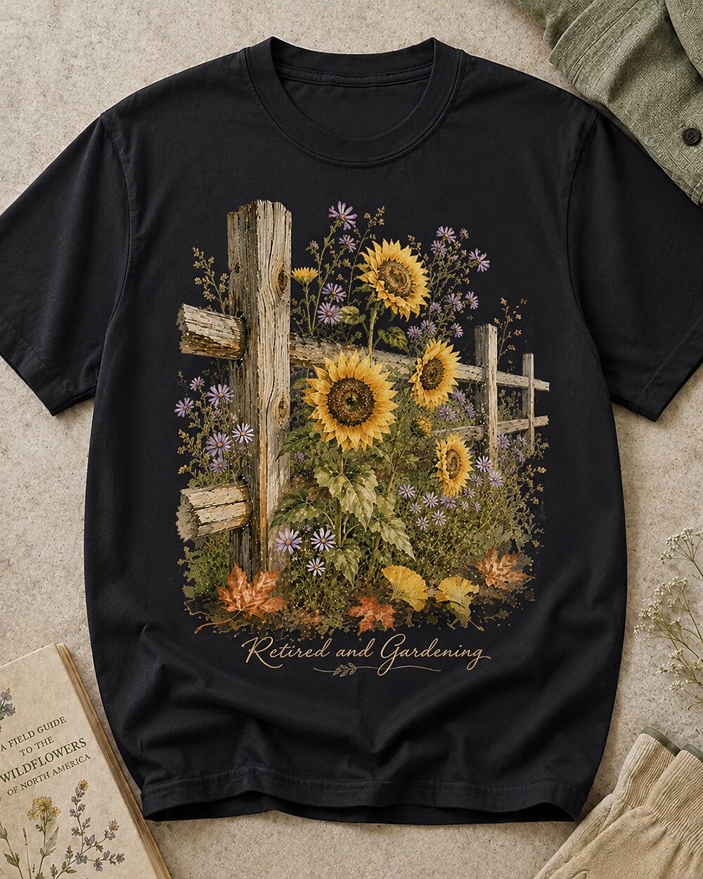 Women's black cotton T-shirt with sunflowers beside a rustic wooden fence, front view.