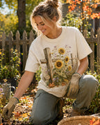 Woman wearing a off white cotton T-shirt with sunflowers beside a rustic wooden fence outdoors.