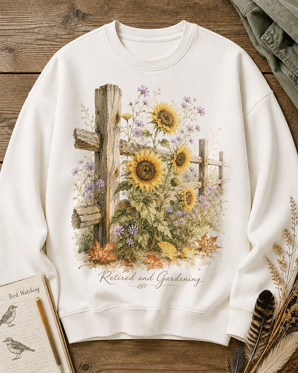 Women's white crewneck sweatshirt with sunflowers beside a rustic wooden fence, front view.