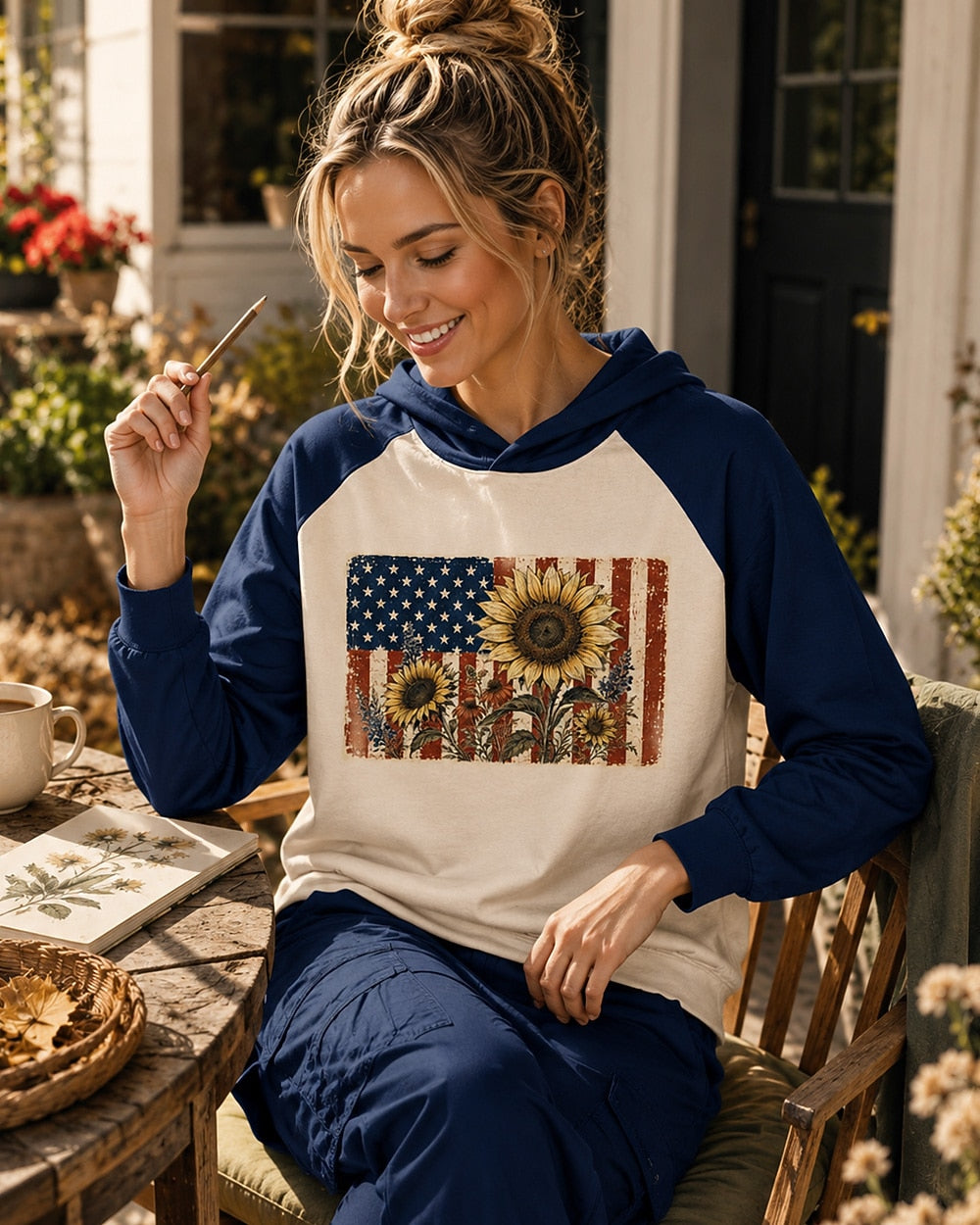 Woman wearing a navy cream sun hoodie with yellow sunflowers and an American flag outdoors.